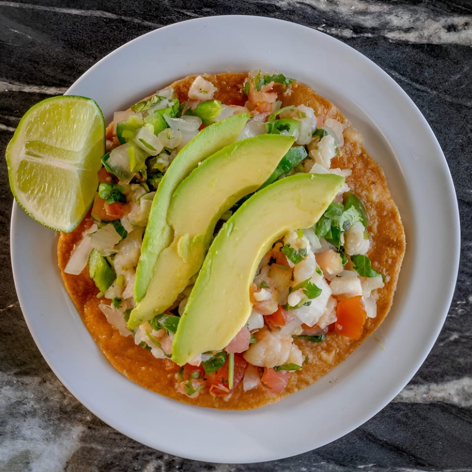 Mangonadas Mexican Kitchen's tostada with shrimp ceviche, avocado slices, and a lime wedge.