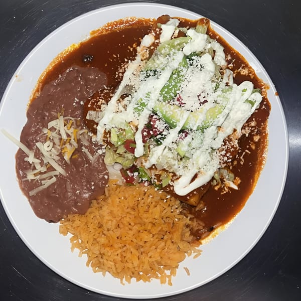 Mangonadas Mexican Kitchen's enchiladas covered in red sauce, topped with lettuce, avocado, and sour cream, served with rice and refried beans.