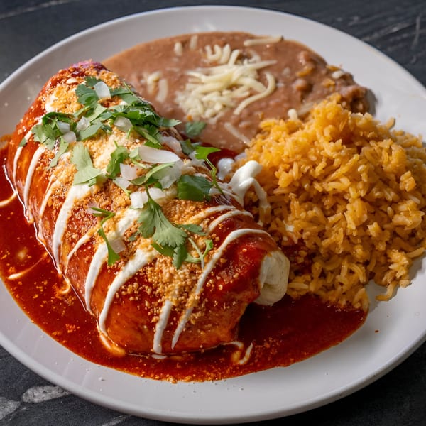 A Mangonadas Mexican Kitchen burrito covered in red sauce, crema, and cilantro, with rice and beans.